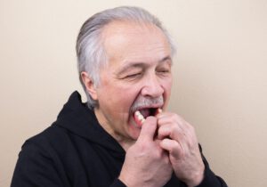 Zahnprothese einsetzen nach dem Aufbringen von Haftpulver